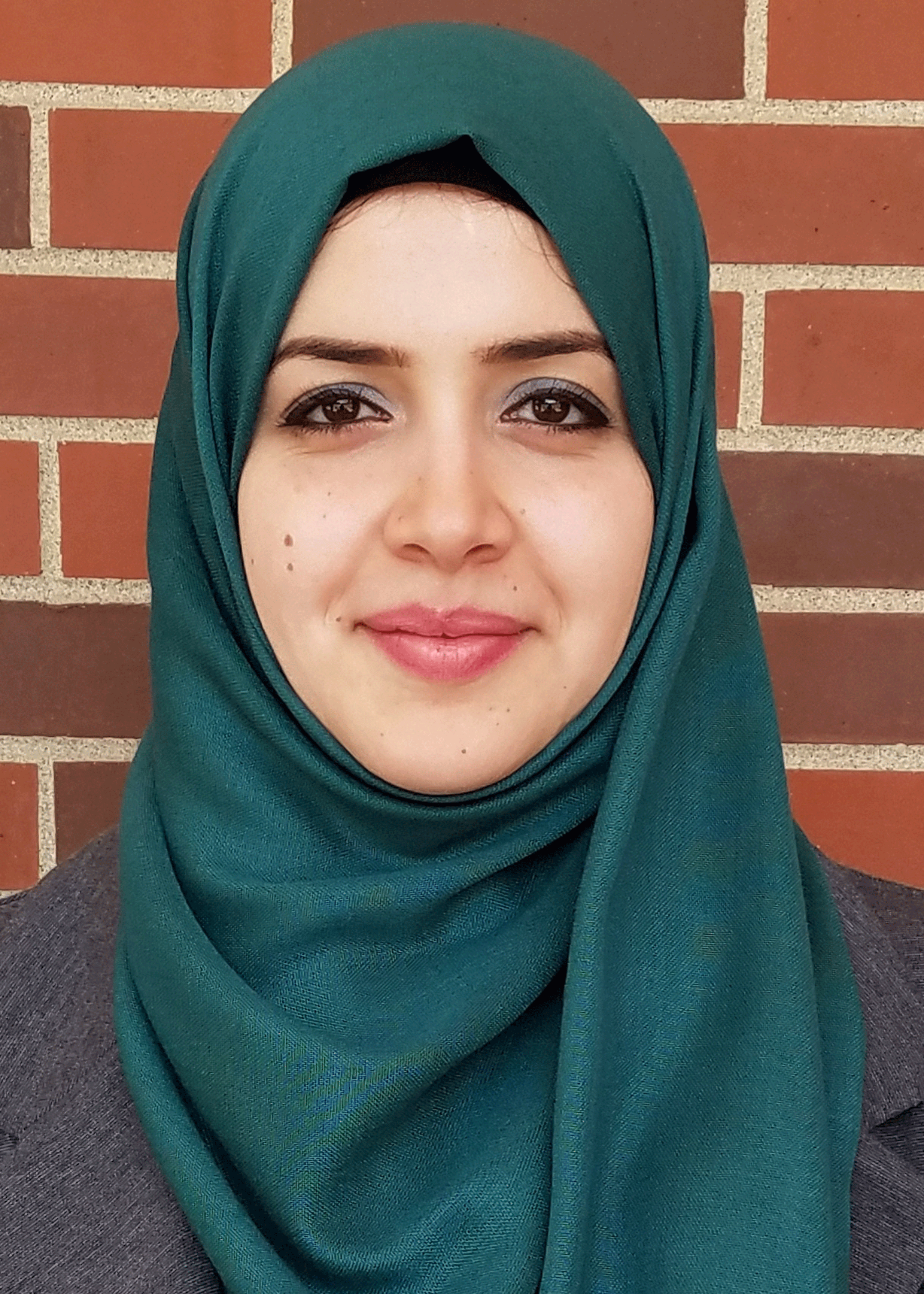 Mason assistant professor Doaa Bondok wears a teal hijab and gray suit in her faculty profile