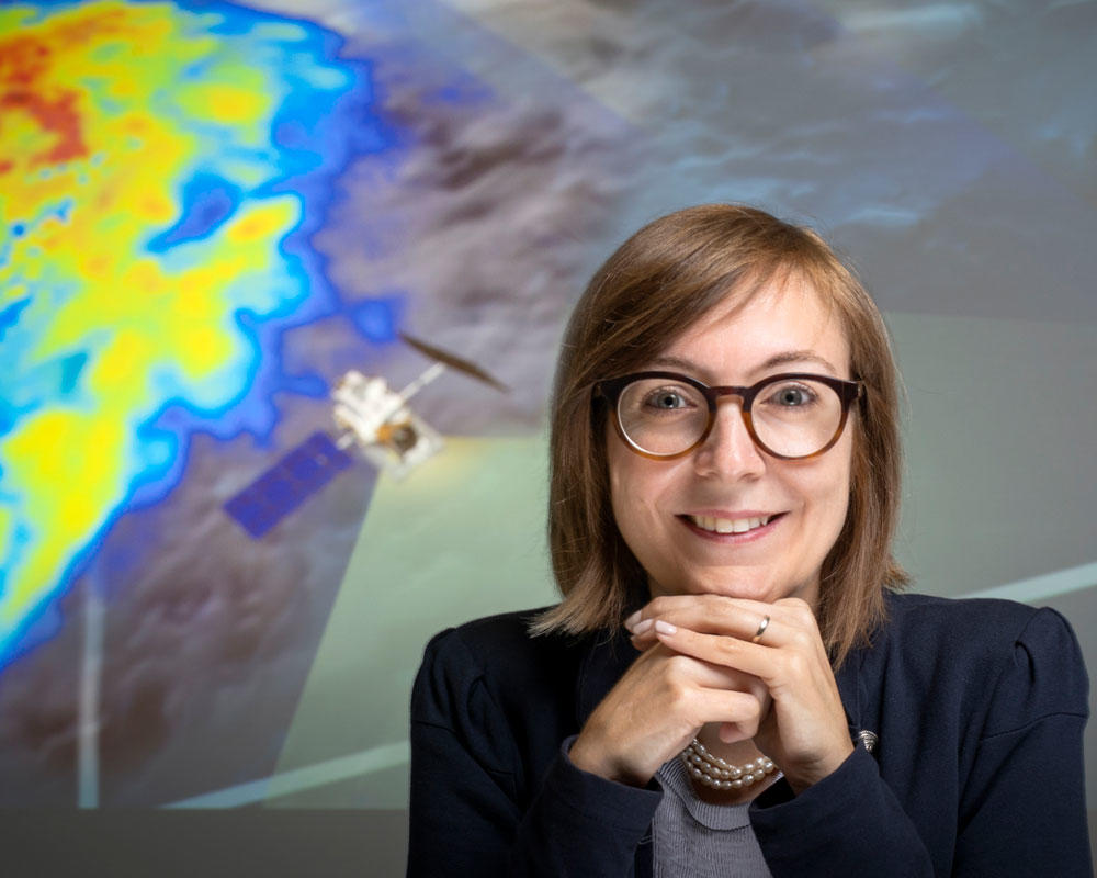 Viviana Maggioni portrait in front of projection of satellite imagery of precipitation
