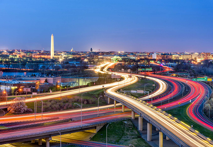 A photo of the DC skyline at night with a colorful busy highway.